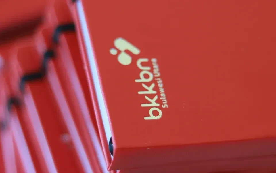 Stack of red BKKBN-branded notebooks, gold foil logo